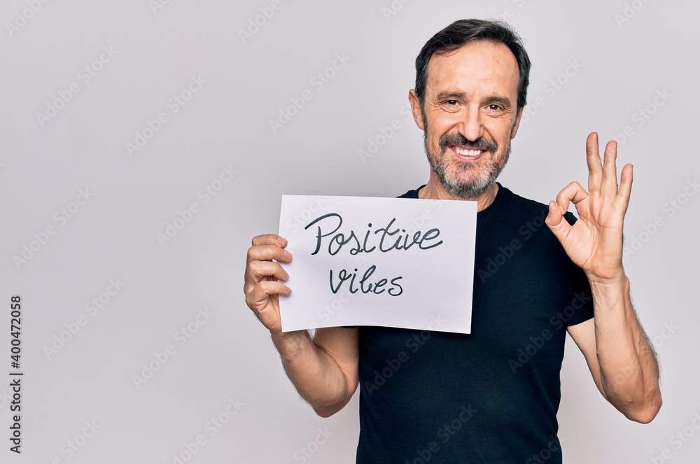 Middle age handosme man asking for good attitude holding paper with positive vibes message doing ok sign with fingers, smiling friendly gesturing excellent symbol Middle age handosme man asking for good attitude holding paper with positive vibes message doing ok sign with fingers, smiling friendly gesturing excellent symbol