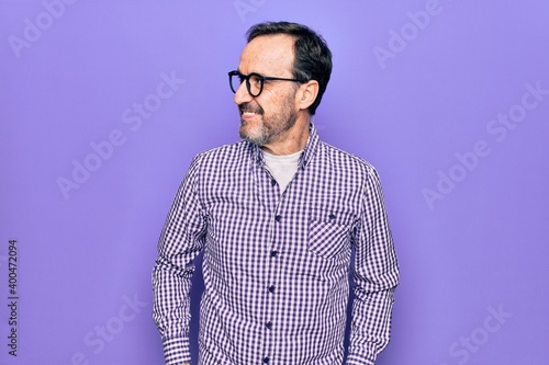 Middle age handsome man wearing casual shirt and glasses over isolated white background looking to side, relax profile pose with natural face and confident smile. © Krakenimages.com
