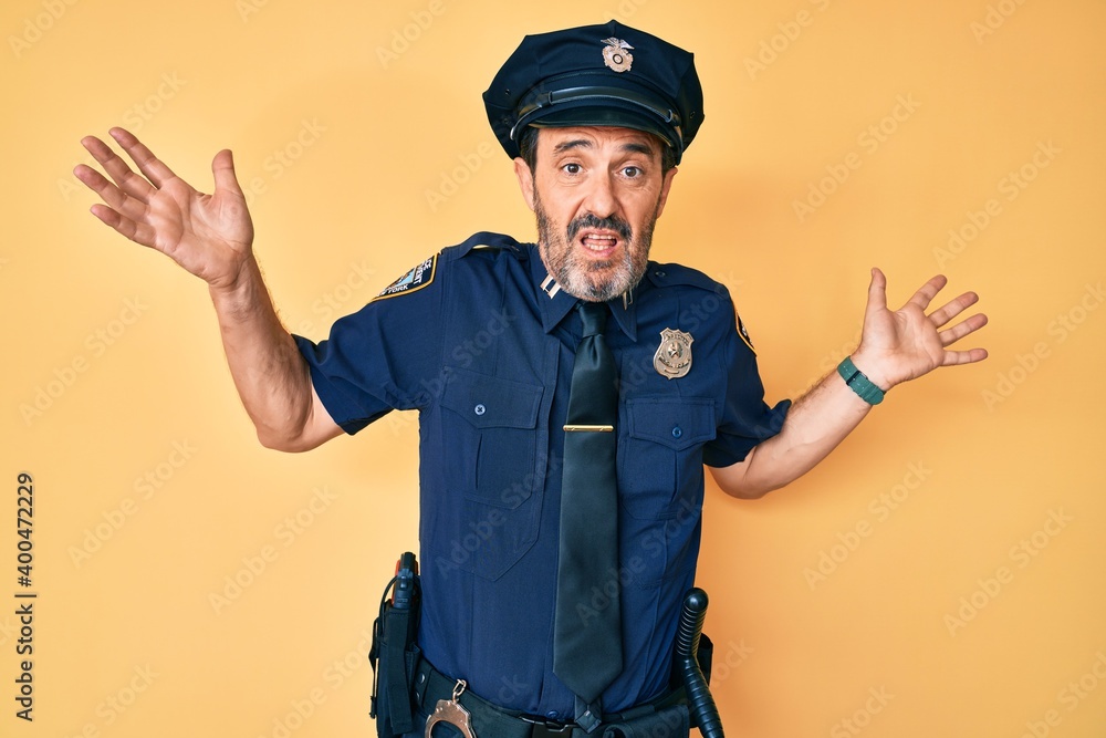 Middle age hispanic man wearing police uniform clueless and confused expression with arms and hands raised. doubt concept. Middle age hispanic man wearing police uniform clueless and confused expression with arms and hands raised. doubt concept.