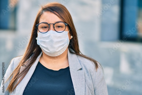 Young hispanic plus size businesswoman wearing medical mask standing at the city.