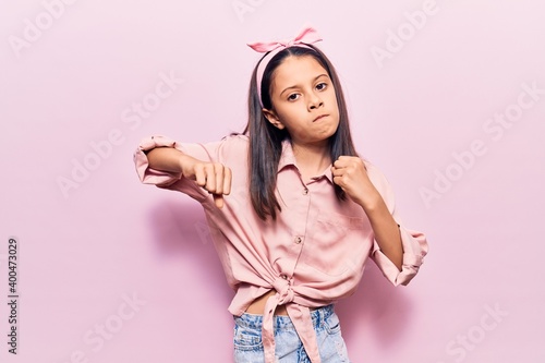 Beautiful child girl wearing casual clothes punching fist to fight, aggressive and angry attack, threat and violence