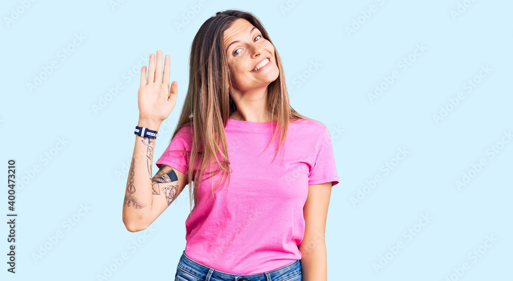 Beautiful caucasian woman wearing casual clothes waiving saying hello happy and smiling, friendly welcome gesture Beautiful caucasian woman wearing casual clothes waiving saying hello happy and smiling, friendly welcome gesture