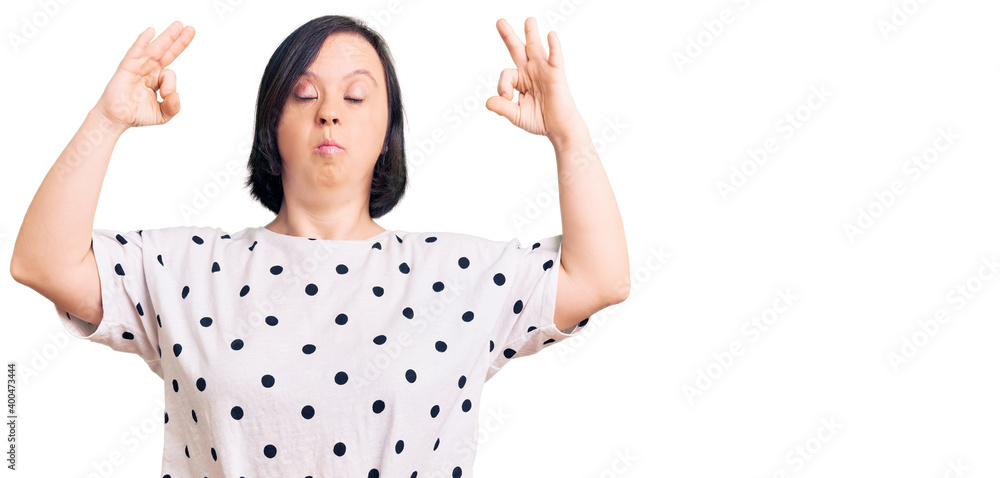 Brunette woman with down syndrome wearing casual clothes relax and smiling with eyes closed doing meditation gesture with fingers. yoga concept. Brunette woman with down syndrome wearing casual clothes relax and smiling with eyes closed doing meditation gesture with fingers. yoga concept.