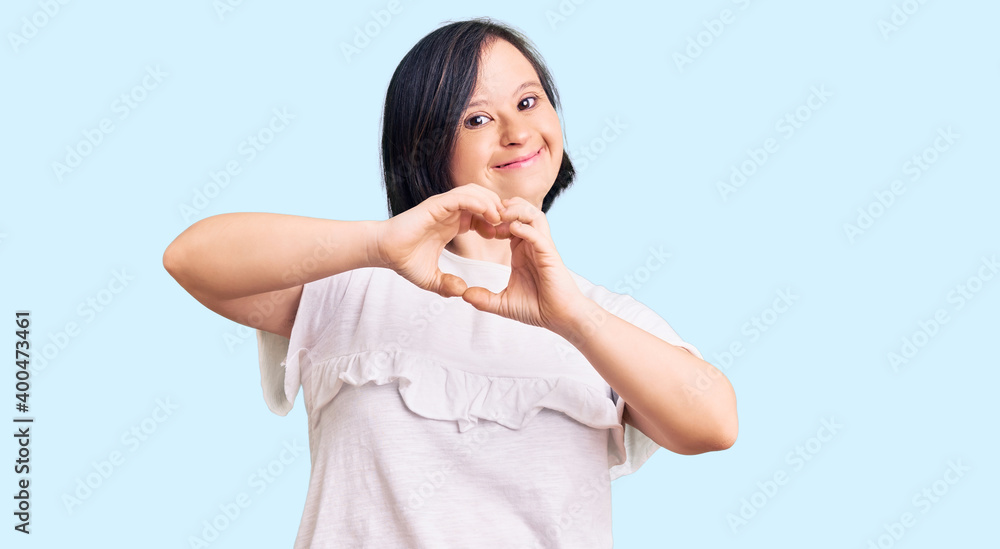 Brunette woman with down syndrome wearing casual white tshirt smiling in love doing heart symbol shape with hands. romantic concept. Brunette woman with down syndrome wearing casual white tshirt smiling in love doing heart symbol shape with hands. romantic concept.