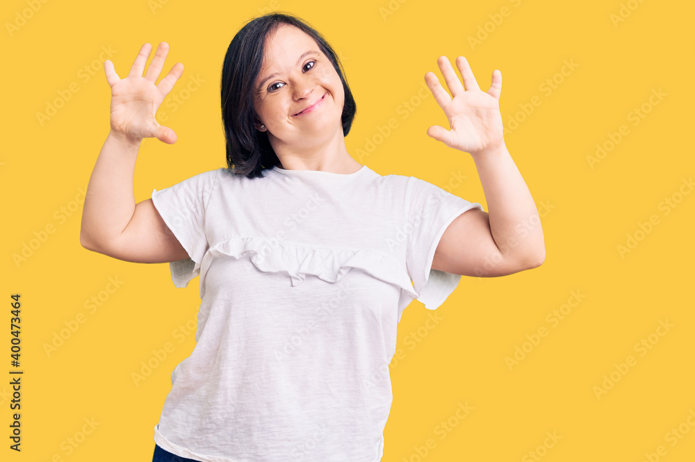 Brunette woman with down syndrome wearing casual white tshirt showing and pointing up with fingers number ten while smiling confident and happy. Brunette woman with down syndrome wearing casual white tshirt showing and pointing up with fingers number ten while smiling confident and happy.