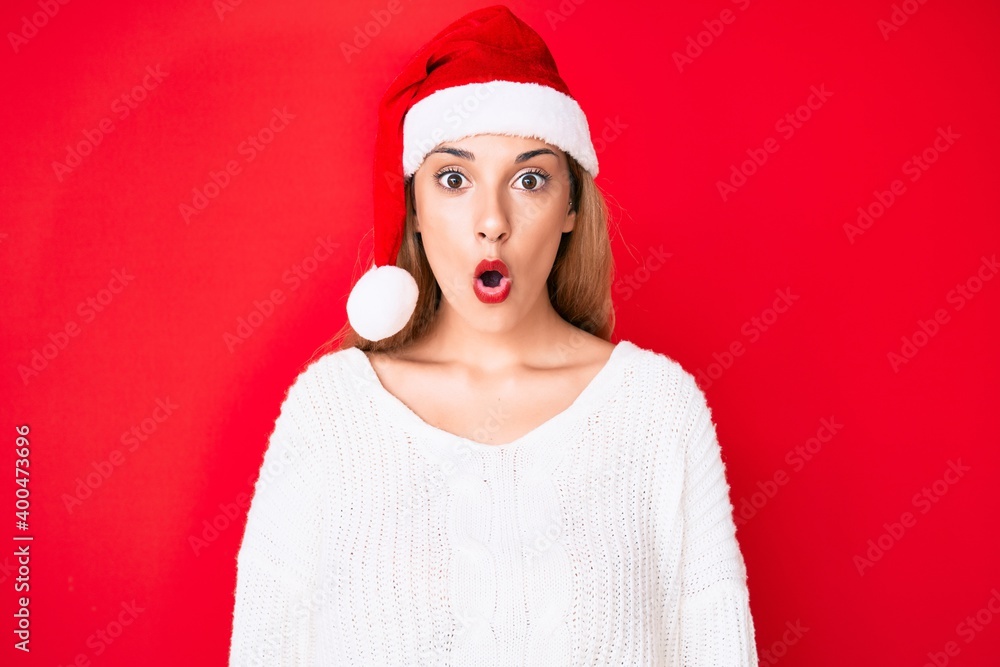 Young brunette woman wearing christmas hat scared and amazed with open mouth for surprise, disbelief face Young brunette woman wearing christmas hat scared and amazed with open mouth for surprise, disbelief face