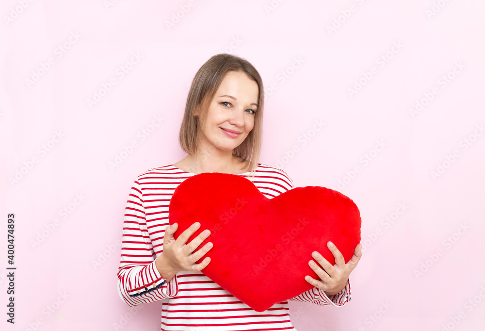 Pretty smiling woman with heart pillow in hands. Pretty smiling woman with heart pillow in hands.