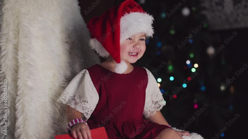 a child in red clothes is sitting waiting for the new year. the concept of celebrating Christmas at midnight. holiday costume. a girl writes a letter to Santa Claus. wish list a child in red clothes is sitting waiting for the new year. the concept of celebrating Christmas at midnight. holiday costume. a girl writes a letter to Santa Claus. wish list