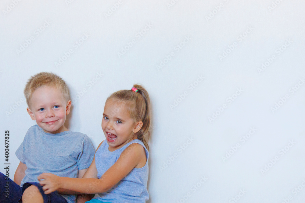 a boy and a girl are sitting on the floor. Children together at home a boy and a girl are sitting on the floor. Children together at home
