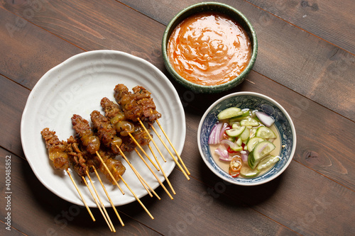 beef satay grilled and spicy peanut sauce on wooden background