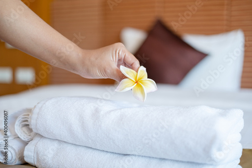 A hotel maid stacked towels on the bed and placed flowers on the towels in a hotel room