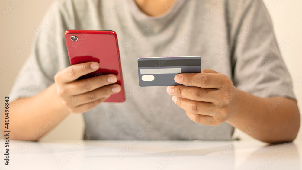 Asian man paying by credit card online while ordering on the internet at home, transaction idea using mobile banking application. Asian man paying by credit card online while ordering on the internet at home, transaction idea using mobile banking application.