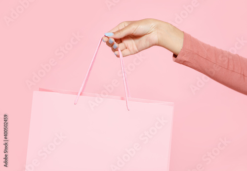 Store opening and discounts for customers. Hand of young african american lady holding pink shopping bag photo