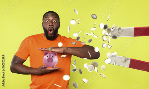 Man tries to protect his piggybank from a big magnet that ruba steals money. concept of money fraud and theft. Green background photo