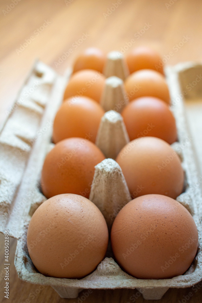 Closeup brown egg in a cardboard box from a supermarket on a wooden floor. Closeup brown egg in a cardboard box from a supermarket on a wooden floor.