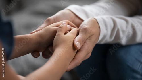 Close up mother supporting, touching adorable little daughter hands, family enjoying tender moment, expressing love and care, mum comforting, caressing kid, childcare, children protection concept