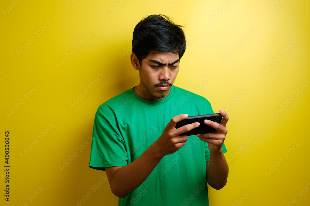 Angry Asian man plays mobile game on his smartphone. Angry Asian man plays mobile game on his smartphone.