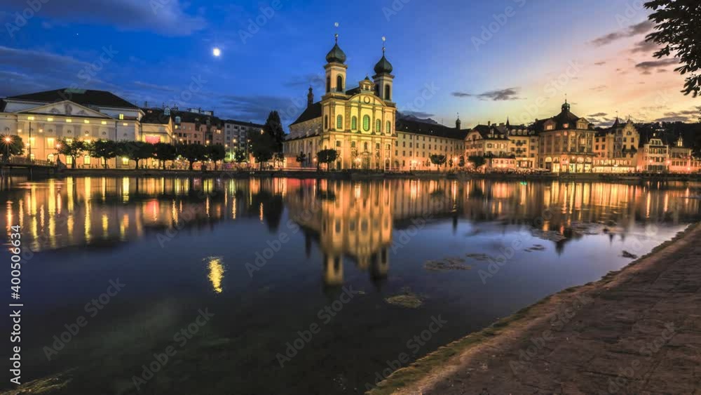 TIME-LAPSE: colorful sunset of Lucerne city on Lake Lucerne in Central Switzerland. Jesuitenkirche or Jesuit Church of St. Francis Xavier reflects on Reuss river. Famous landmark of historical city TIME-LAPSE: colorful sunset of Lucerne city on Lake Lucerne in Central Switzerland. Jesuitenkirche or Jesuit Church of St. Francis Xavier reflects on Reuss river. Famous landmark of historical city