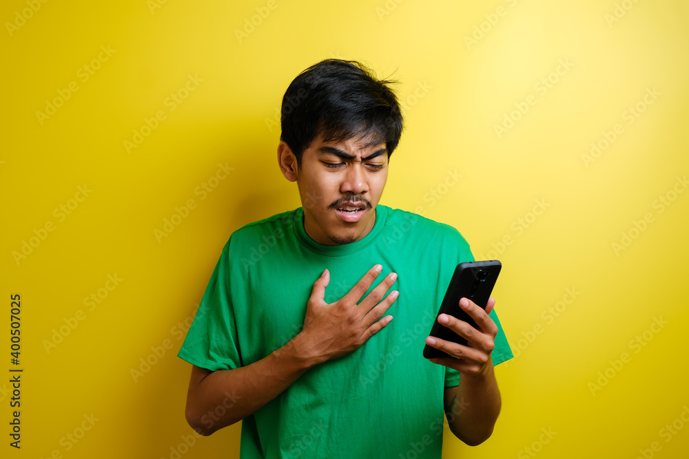 Attractive young asian man reading texting chatting on his phone, bad news, sad crying expression Attractive young asian man reading texting chatting on his phone, bad news, sad crying expression