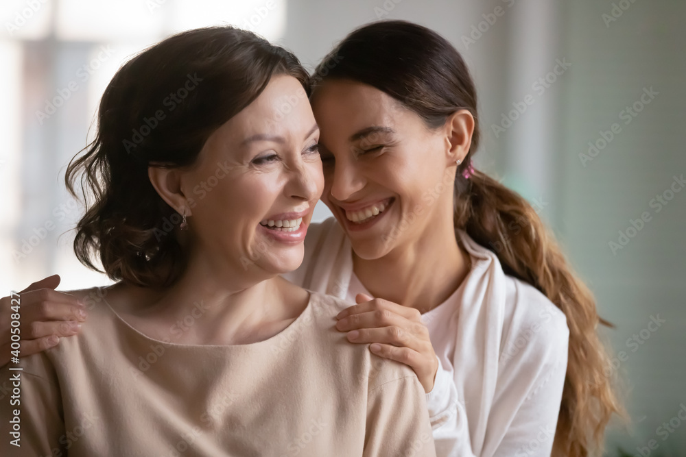 Close up overjoyed middle aged mother and grownup daughter cuddling, enjoying tender moment, leisure time, excited young woman touching mature mum shoulders, good family relationship, two generations Close up overjoyed middle aged mother and grownup daughter cuddling, enjoying tender moment, leisure time, excited young woman touching mature mum shoulders, good family relationship, two generations