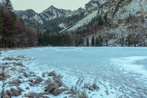 Gefrorener Bergsee im Chiemgau vor Bergen mit Schnee photo