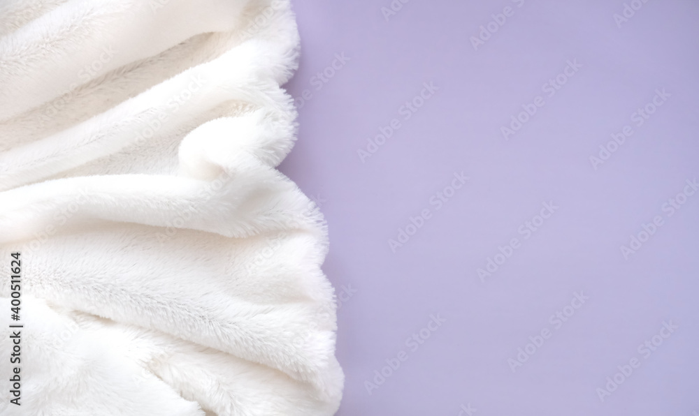 White delicate soft background of plush fabric folds on light violet background. Copy space. Flat lay. Details of warm winter clothes White delicate soft background of plush fabric folds on light violet background. Copy space. Flat lay. Details of warm winter clothes