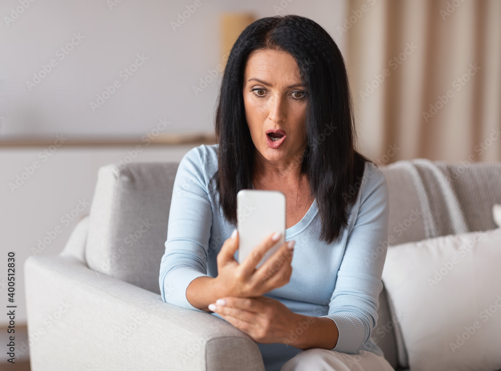 Surprised shocked mature woman using mobile phone Surprised shocked mature woman using mobile phone