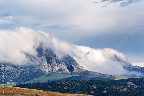 Peña negra with clouds on the peaks, rocky mountain in the Sierra de Camarolos in Villanueva de Cauche, Malaga.