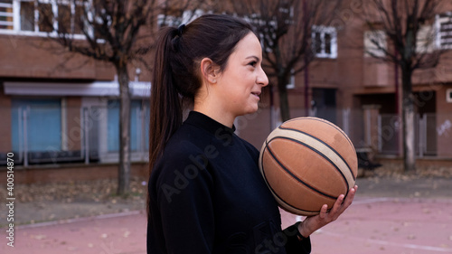 The Caucasian basketball player holding the ball in her hand is surrounded by buildings © Alberto Cotilla