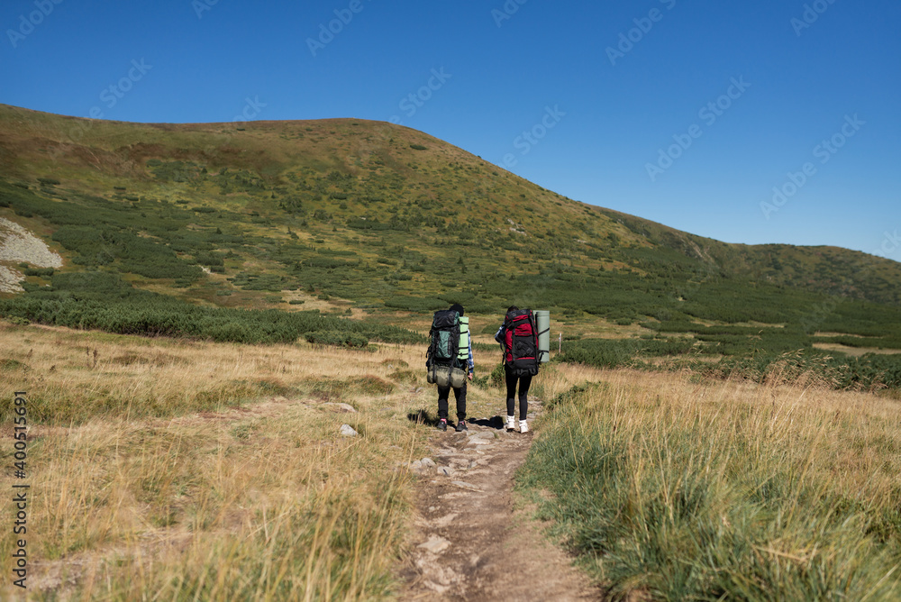 couple in love tourists man and woman are walking along a mountain path. back view. Hiking concept.