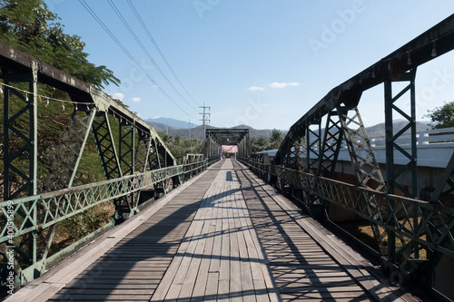 Old iron bridge over the river in Thailand. Sunlight and ancient bridge with clear sky.