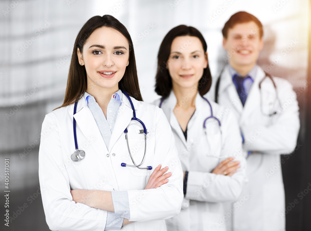 Group of young professional doctors standing as a team with arms crossed in sunny hospital. Medical help, insurance in health care, best disease treatment and medicine concept Group of young professional doctors standing as a team with arms crossed in sunny hospital. Medical help, insurance in health care, best disease treatment and medicine concept