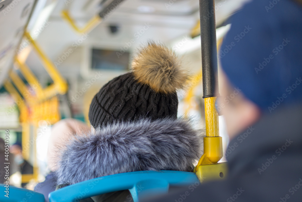Back view of hiker traveler, woman in woolen hat sitting inside the bus in winter season.