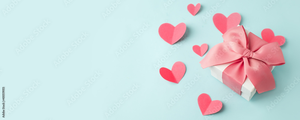 Stylish gift box with big pink bow and tender paper craft pink hearts on blue background, copy space, Greeting card, banner, flyer, postcard for Saint Valentine day, romance holiday, wedding, birthday Stylish gift box with big pink bow and tender paper craft pink hearts on blue background, copy space, Greeting card, banner, flyer, postcard for Saint Valentine day, romance holiday, wedding, birthday