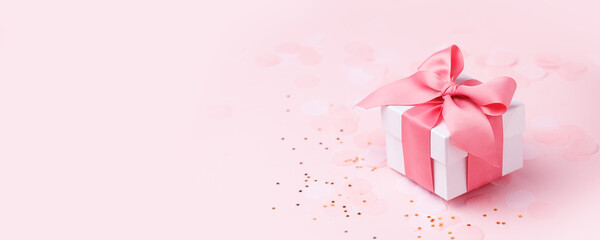 Holiday pink background with gift, white satin bow, ribbon. Valentine's Day, Happy Women's Day, Mother's Day, Birthday, Wedding, Christmas. space for text, banner, flyer