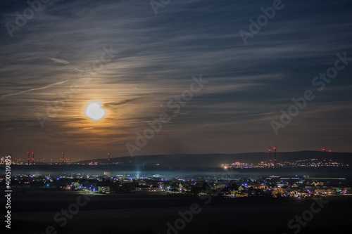 illuminated city with bright moon on the night sky © thomaseder