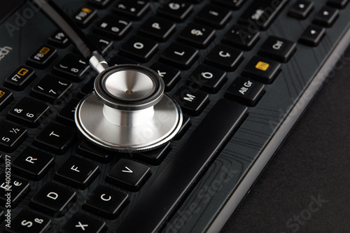 Stethoscope on black computer keyboard. Computer repair service or online health care concept