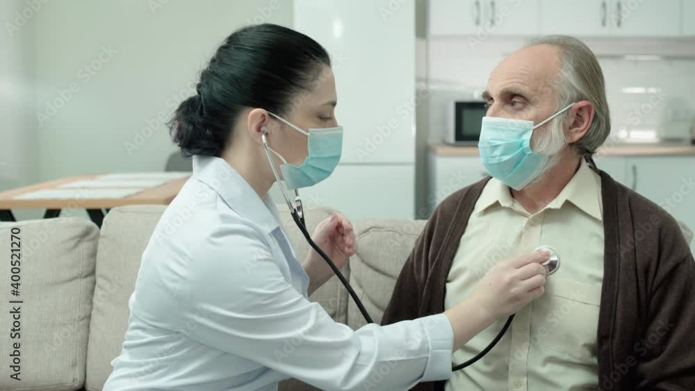 Female doctor in mask checking patient's lungs, using stethoscope, health care Female doctor in mask checking patient's lungs, using stethoscope, health care