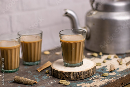 Photography Indian chai in glass cups with metal kettle and other masalas to make the tea