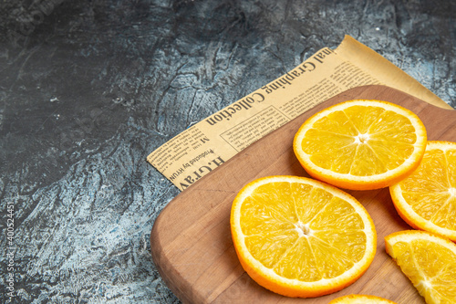 Top view of fresh lemon slices on wooden board on newspaper on gray background photo