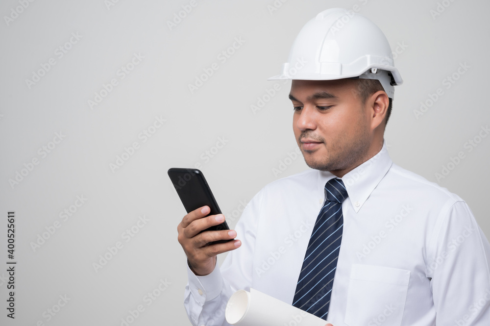 Asian engineer talking with customer on phone to home service. Worker wearing hard hat using smartphone standing on isolated white background. Asian engineer talking with customer on phone to home service. Worker wearing hard hat using smartphone standing on isolated white background.
