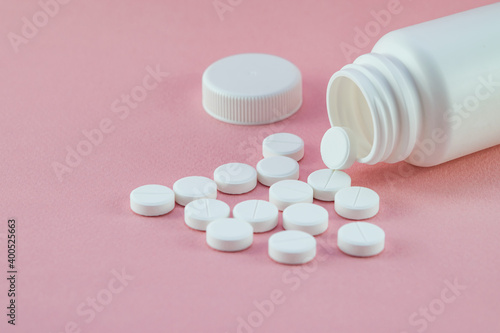 White tablets, vitamin C with a plastic jar for the treatment of coronavirus, cavid-19, and other diseases on a pink background, copy space, top view, close-up, disease treatment theme