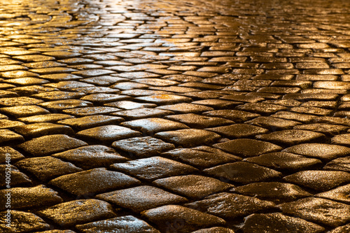 Wet cobblestones at night after rain on a street or road surface, bottom view