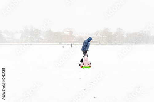 a man is walking with kid on sled