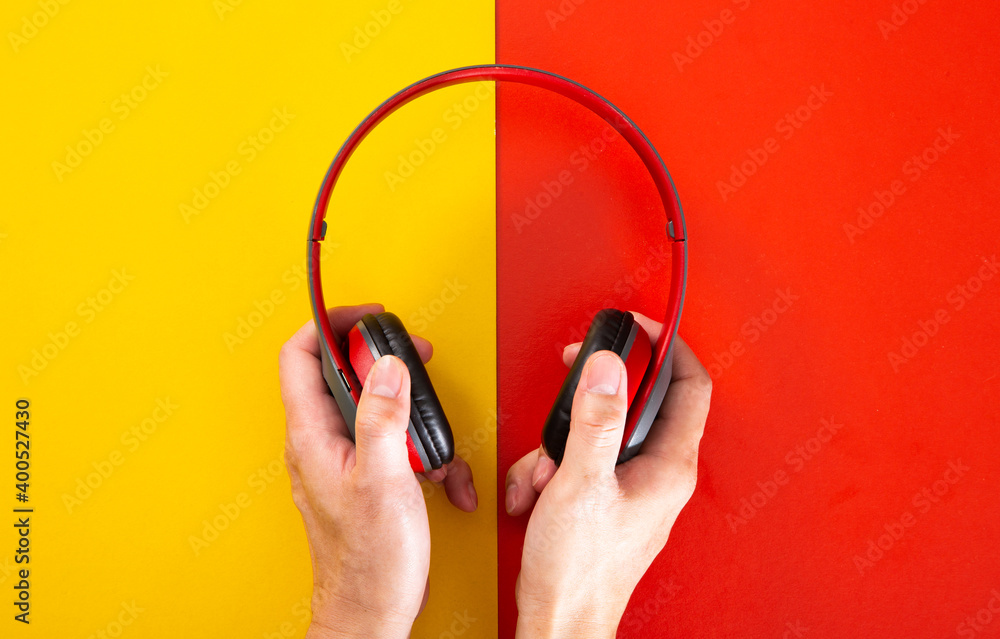 hand holding a headphones on red and yellow background. hand holding a headphones on red and yellow background.