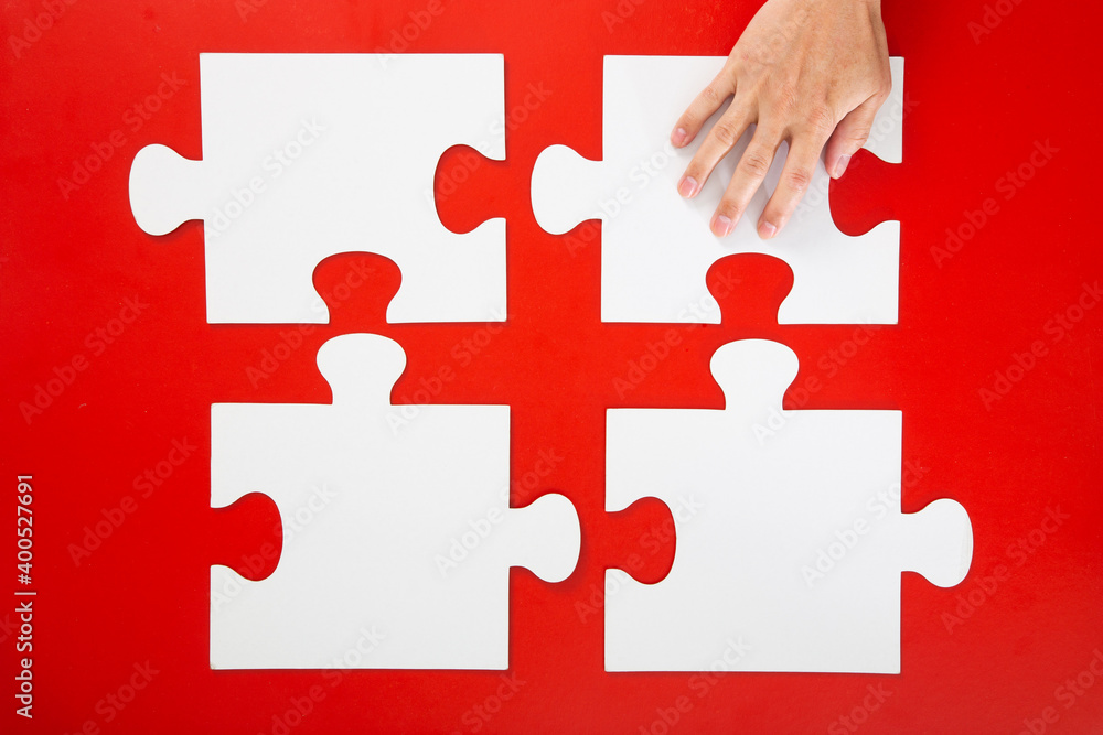 Obraz premium hand solving a puzzle piece on red background.