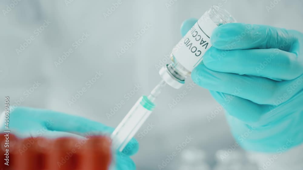 Doctor picks up coronavirus vaccine with a syringe, macro shot Doctor picks up coronavirus vaccine with a syringe, macro shot