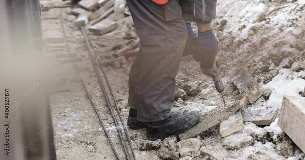A construction company worker drills a hole in a wooden board. Work on the street in winter in difficult conditions A construction company worker drills a hole in a wooden board. Work on the street in winter in difficult conditions