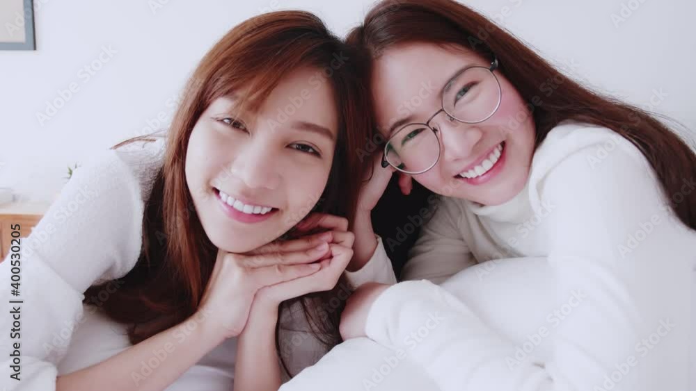 Homosexual Asian women lesbian couple lying on the bed looking at the camera. LGBT friendship concept.\ Homosexual Asian women lesbian couple lying on the bed looking at the camera. LGBT friendship concept.\