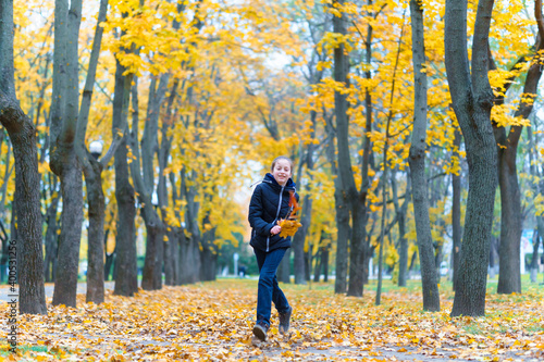 a girl running through the park and enjoys autumn, beautiful nature with yellow leaves